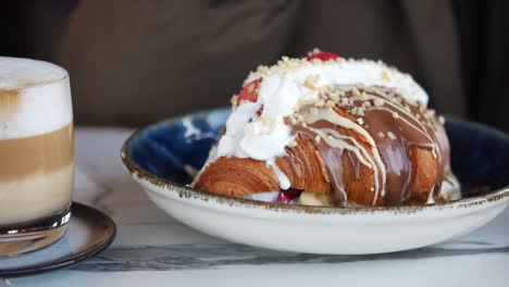 person eating a chocolate croissant with whipped cream and strawberries