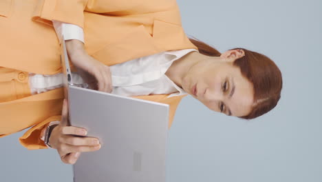 vídeo vertical de una mujer de negocios satisfecha mira la computadora portátil y aprueba.