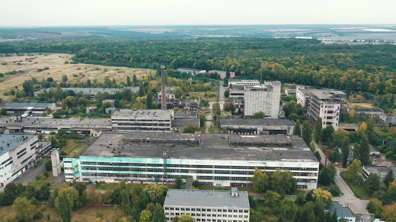 Large industrial territory on nature background. Many buildings of abandoned factory in the countryside. View from above.