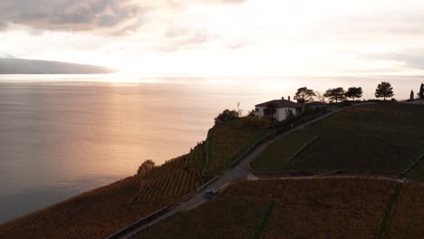 Jib-down-of-house-at-hillside-against-the-backdrop-of-a-beautiful-lake-at-sunset