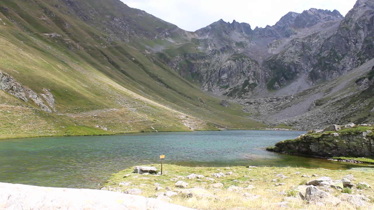 bastante lago de montaña dentro del valle, con los alpes al fondo