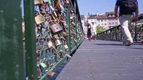 los peatones cruzan el puente peatonal con cerraduras de amor colgando de la valla de la barandilla en la ciudad de zúrich en una soleada tarde de primavera.