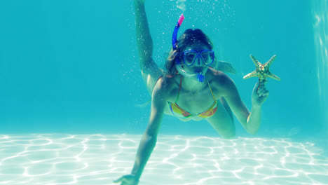 happy blonde jumping into swimming pool wearing snorkel and holding starfish