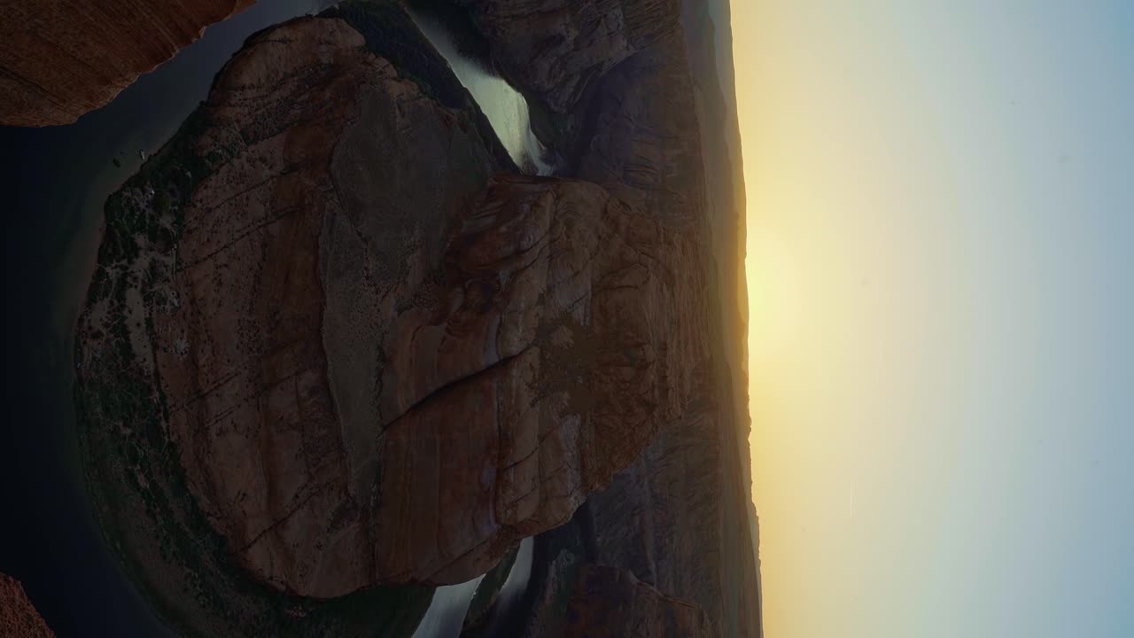 Wide pan right landscape shot revealing the famous Horseshoe bend colorful sandstone rock formation formed from the Colorado river near Page, Arizona during a sunny spring evening golden sunset
