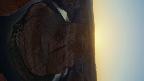 Wide-pan-right-landscape-shot-revealing-the-famous-Horseshoe-bend-colorful-sandstone-rock-formation-formed-from-the-Colorado-river-near-Page,-Arizona-during-a-sunny-spring-evening-golden-sunset