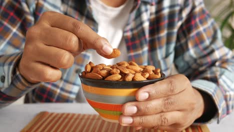 person eating almonds from a bowl