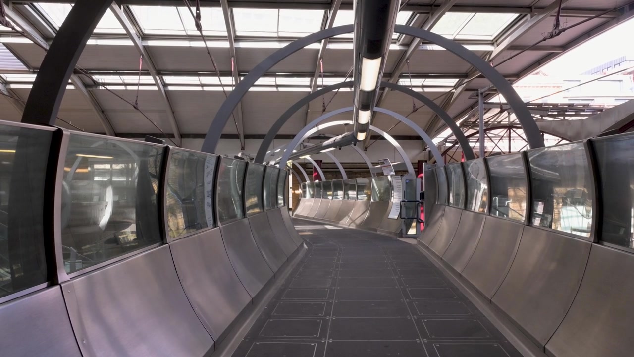 Tunnel pedonale curvo all'interno della stazione di Farringdon con archi in acciaio e pannelli di vetro in piena luce diurna
