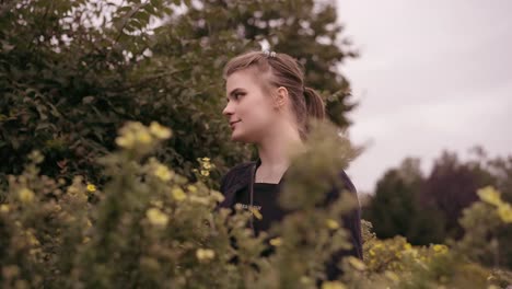 close up shot of a young female looking around dense green bushes in a garden on a cloudy day