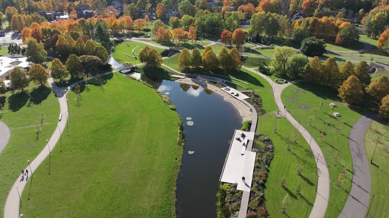 Drone captures Victory Park in Riga Latvia with autumn trees, curved paths, pond