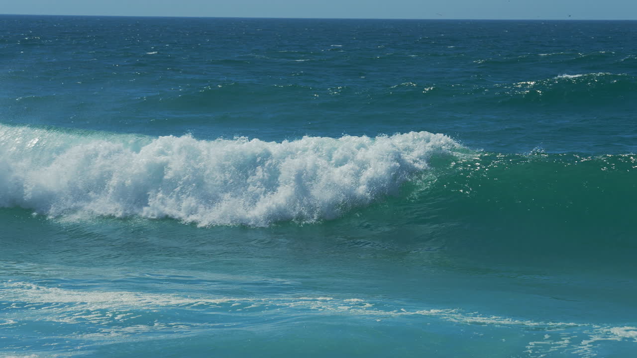 tiro de cámara lenta de primer plano de las olas del mar rompiendo en la costa arenosa en portugal