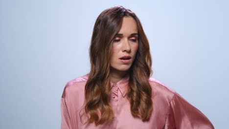 upset businesswoman standing on blue background. girl with sad face expression