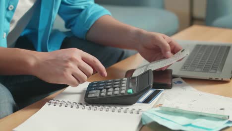 cerca de la mano del hombre sosteniendo el billete y calculando el dinero con una calculadora