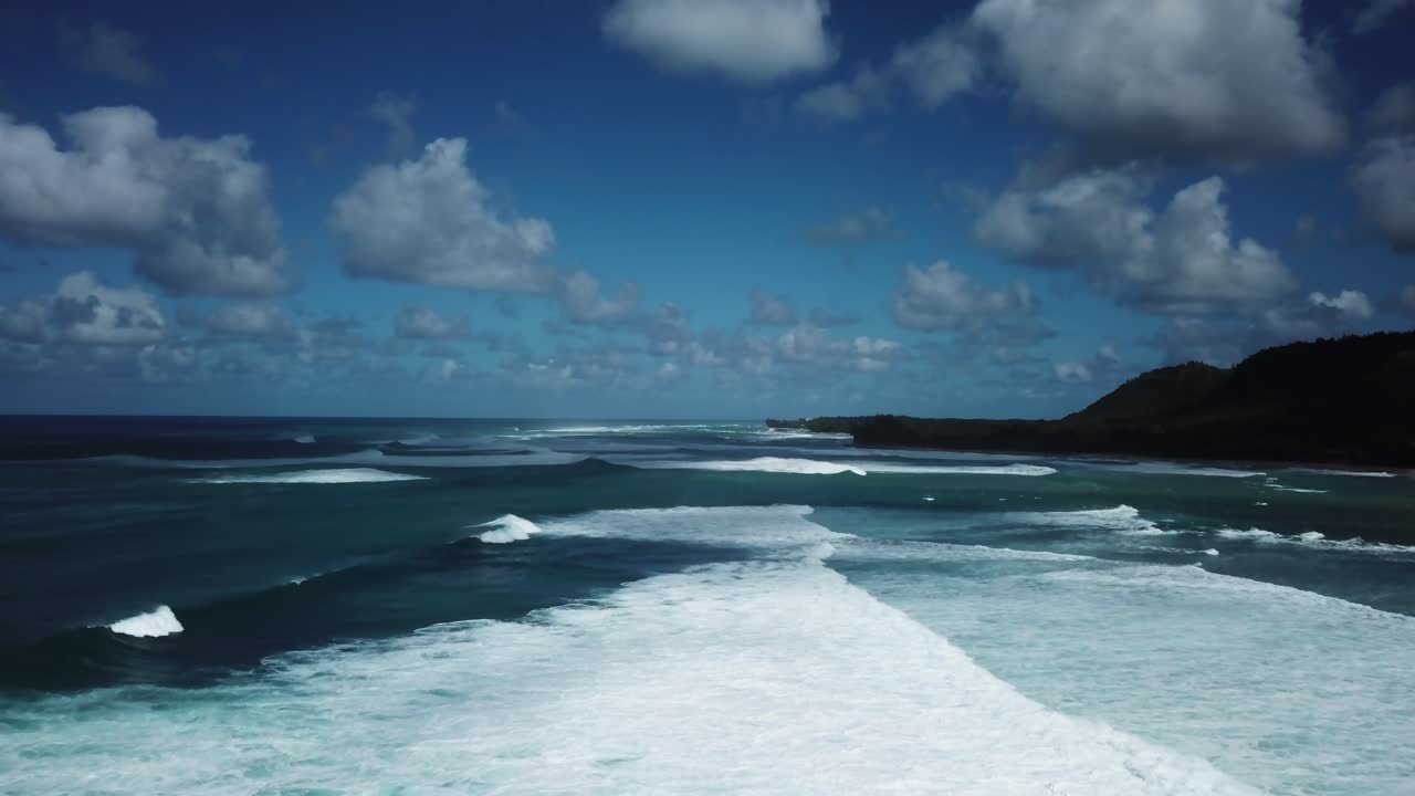 Aerial shot of dozens of rolling waves crashing towards the North Shore coast of Oahu, Hawaii.