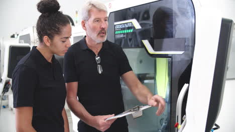 female apprentice working with engineer on cnc machinery