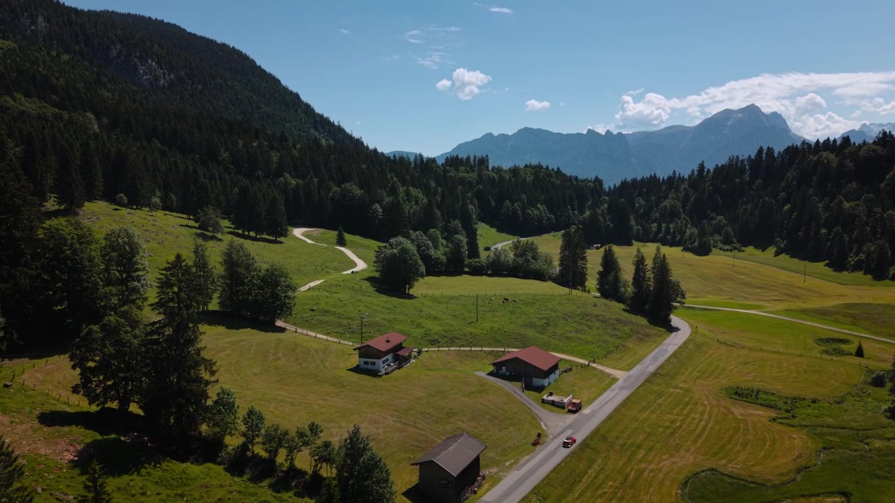 Auto d'epoca rossa, un Maggiolino VW cabriolet, che percorre una strada tra le montagne delle Alpi austriache. Vista aerea.
