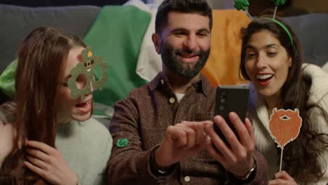 grupo de amigos disfrazándose en casa o en un bar celebrando en la fiesta del día de san patricio posando para una selfie en el teléfono 2
