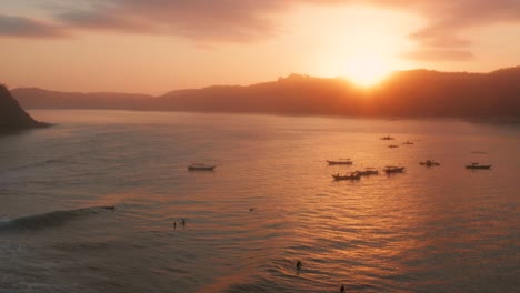 sunrise at the surf spots of gerupuk in lombok, with a view on the bay with the fishing boats and surfers