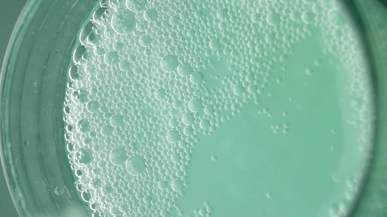 Close-up Top View of Green Liquid with Dissolving Bubbles
