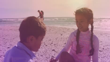 Spots-of-light-against-hispanic-brother-and-sister-high-fiving-each-other-at-the-beach