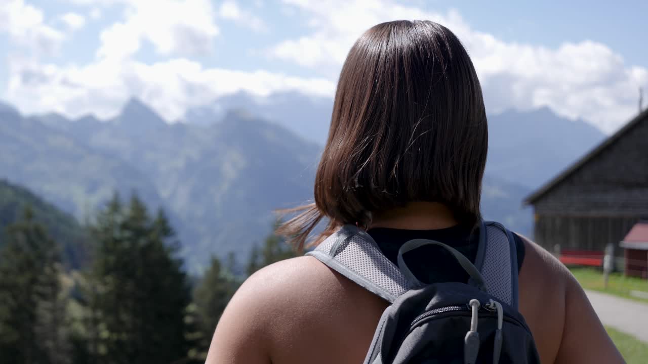 una joven excursionista se pone la mochila y está lista para caminar en las montañas suizas.