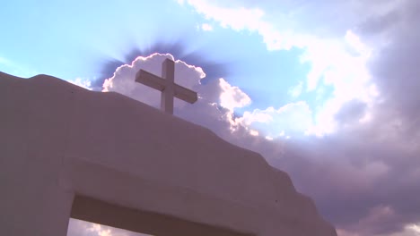 a christian cross glows against a heavenly sky