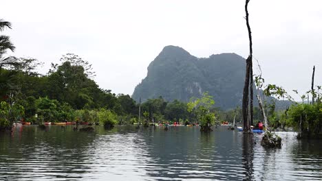 kayakers navigate serene canal with mountain backdrop