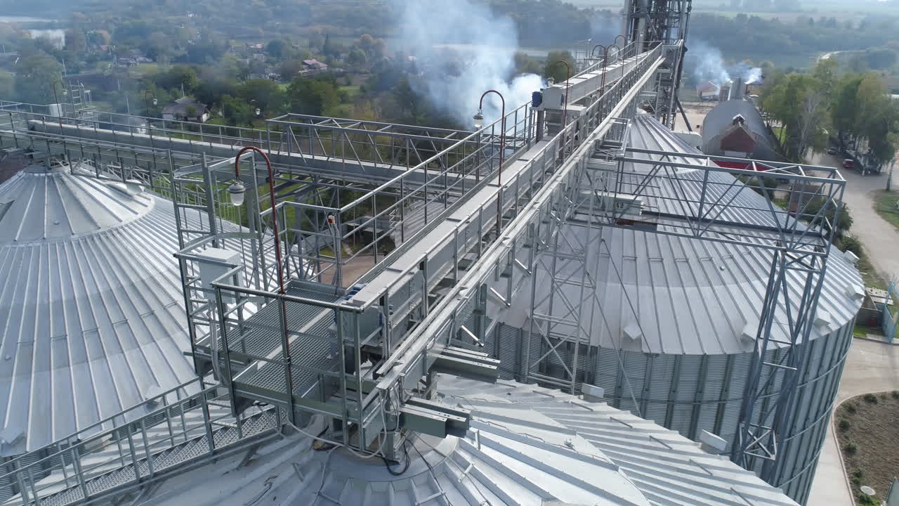 Metal constructions over the grain elevators. Harmful smoke from agricultural factory pollute the air. Aerial view.