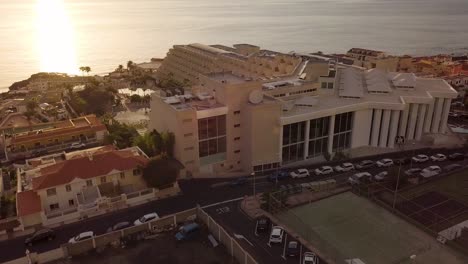 Vista-Aérea-Escénica-De-La-Puesta-De-Sol-Del-Distrito-Residencial-De-La-Isla-De-Tenerife-Con-El-Sol-Brillando-Sobre-El-Agua-Del-Océano