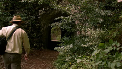 man passing a natural mountain tunnel