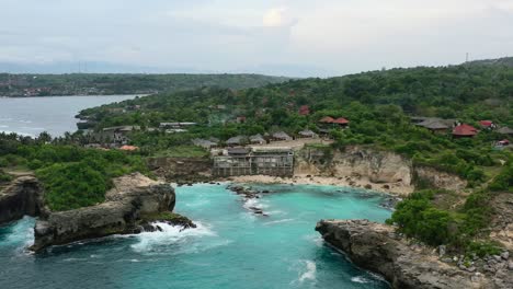 aerial of rocky cliffs at blue lagoon in nusa ceningan on cloudy afternoon sunset