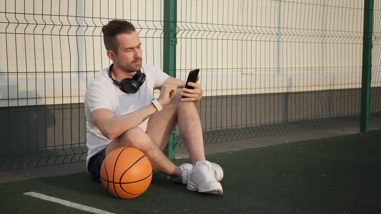 스마트폰을 이용한 농구장에서 앉아 있는 남자