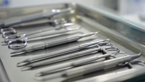 a tray of various surgical instruments is neatly arranged in a sterile environment within a medical facility. each tool is ready for use in an upcoming procedure, ensuring patient safety.