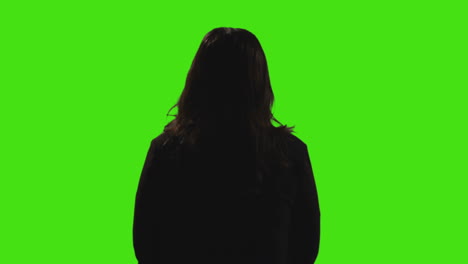 rear view silhouette of young woman standing waiting and looking around against green screen background