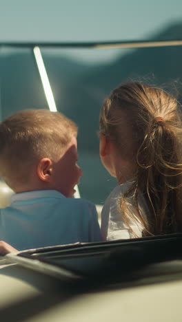 little children look out of motorboat hatch travelling across ocean on sunny day. happy siblings enjoy cruise by fast yacht in sea bay on vacation