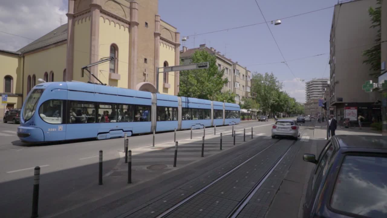 Tilt down reveal of St Peter Catholic Church, light blue public tram stop downtown Zagreb, Croatia