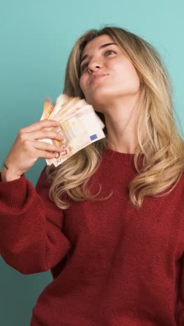rich woman showing euro banknotes in blue studio