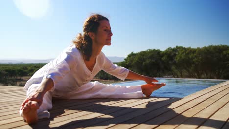 Senior-woman-doing-stretching-exercise-near-poolside-4k