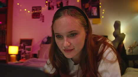 young woman using her laptop on her bed