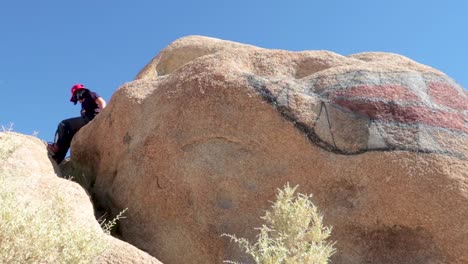 woman cliimbing down a huge rock.