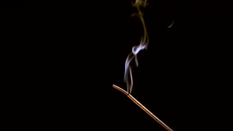 an incense stick burns and smokes.