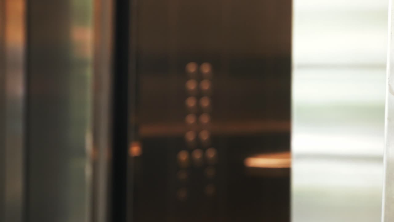 Extreme close-up view of a metal elevator door opening, highlighting the expanding vertical seam and the reflective stainless steel surface
