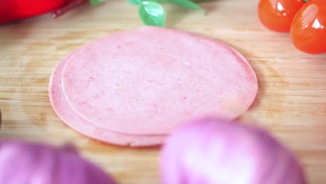 sliced ham on a wooden cutting board with vegetables