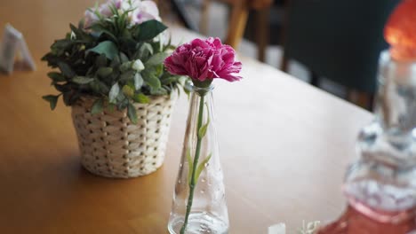 clavel rosa en un jarrón en una mesa de madera