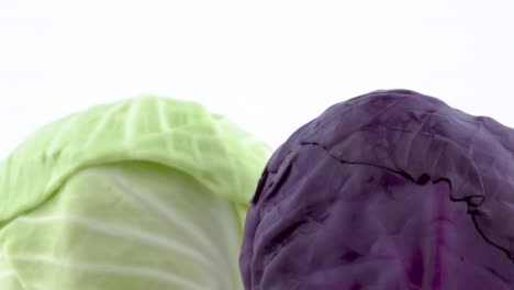 macro shooting of upper part of two whole mini cabbages. slowly rotating on the turntable isolated on the white background. close-up.