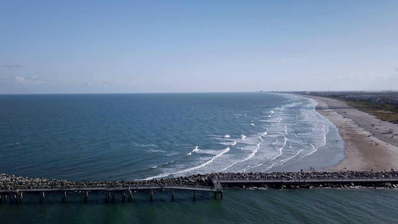costa soleada de puerto cañaveral, florida con olas rodando hacia la playa de arena, mar plano y cielo azul claro