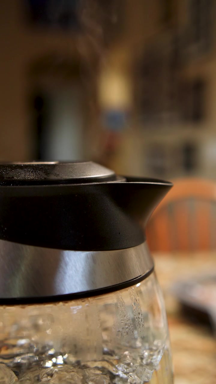 Steam rising from an electric kettle - isolated close up in vertical slow motion