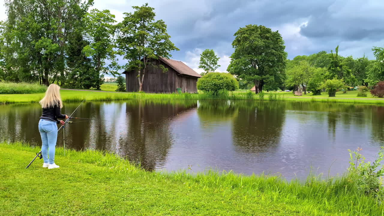 금발 여자 호수 물에서 시 막대기, 아마추어 시 여자 물고기를 잡는