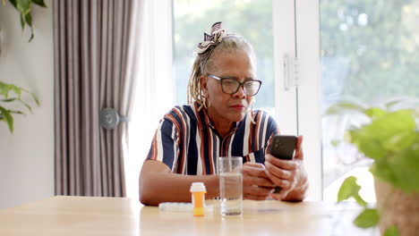 a senior african american woman wearing glasses is looking at smartphone