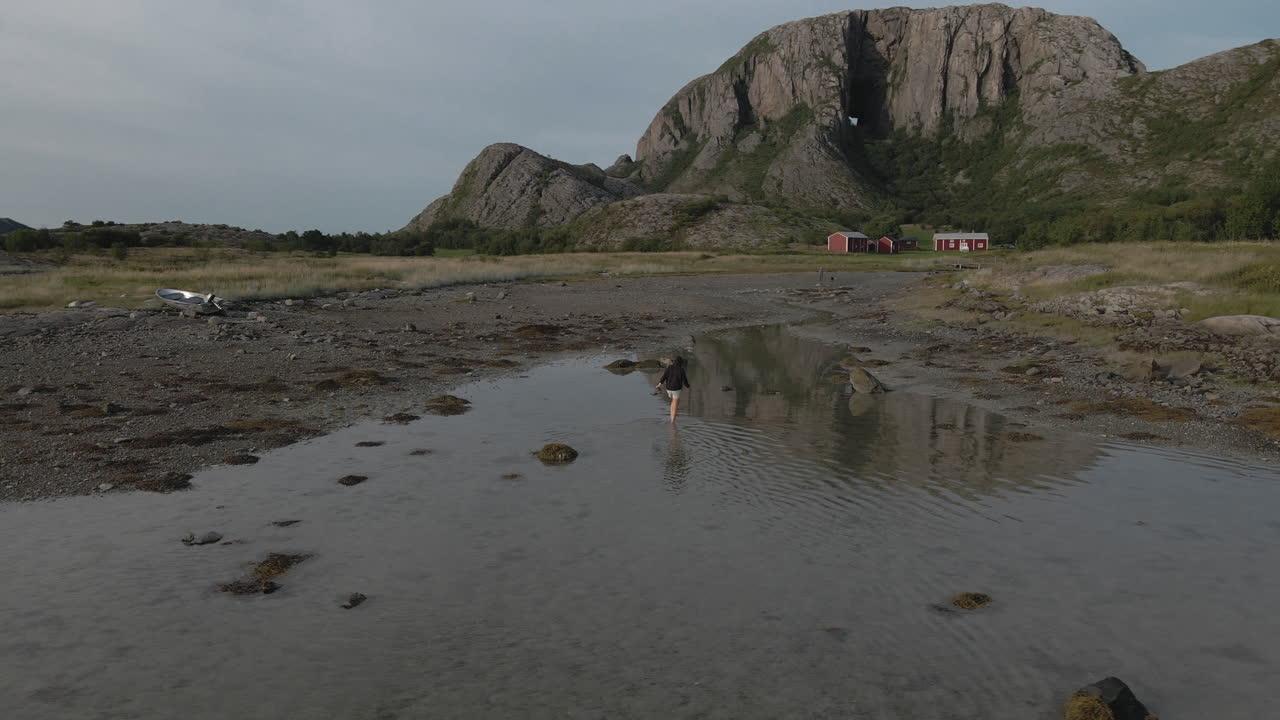 Shallow Water With Female Tourist Walking On Countryside Of Nordland, Norway. - Aerial Orbit