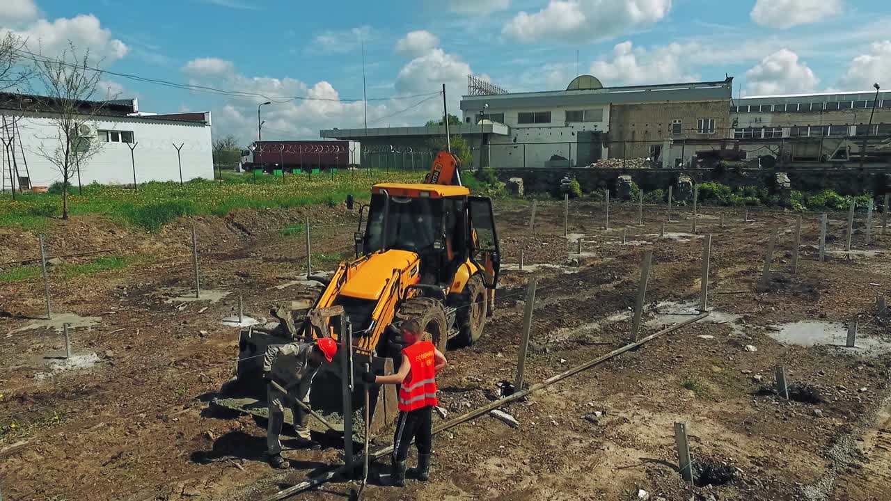 Heavy equipment on construction site. Aerial flight over new constructions site development while heavy machinery and construction workers working with power tools